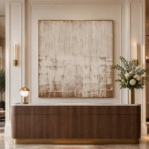 Gold framed cream and brown abstract artwork above a curved hotel lobby console.