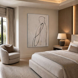 Neutral minimalist wall art viewed beside a calm bedroom sitting area.