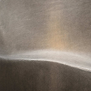 Close-up of the softly raised ivory horizon across taupe texture.