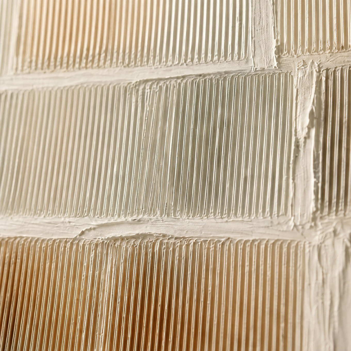 Close-up of warm white combed relief and muted metallic transitions.