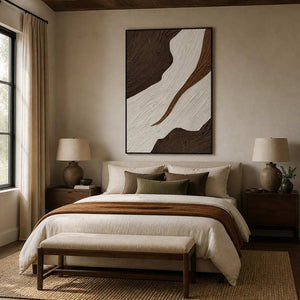 Black-framed brown and ivory abstract wall art above a bed with neutral linens.