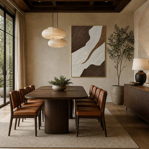 Gold-framed textured abstract wall art behind a wooden dining table with leather chairs.