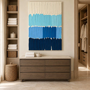 The Sea's Rhythm above a wood cabinet with folded towels beside open storage in a bathroom dry area.