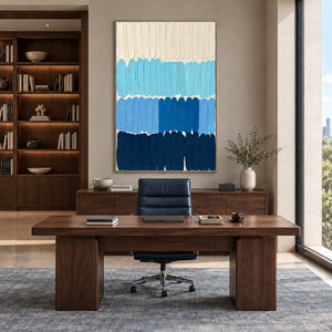 The Sea's Rhythm in a silver frame behind a dark wood desk with a navy office chair.