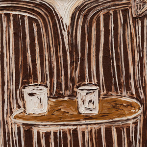 Detail of two white cups on a round brown table beneath striped clothing.