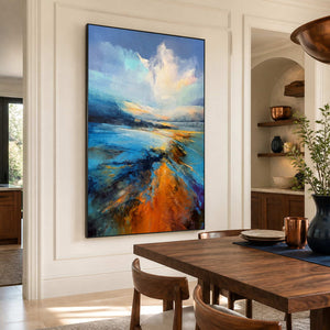 Black framed blue shoreline painting beside a wooden dining table and copper cups.