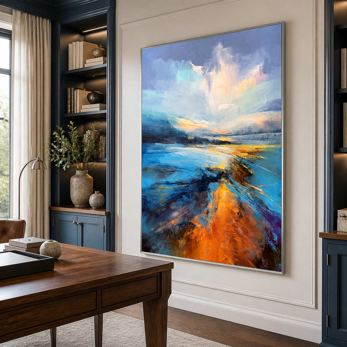 Silver framed shoreline artwork beside a wooden desk and deep blue study shelves.