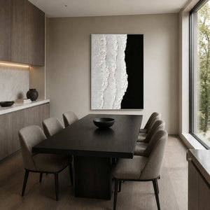 Silver framed black and white abstraction beyond a dark dining table with gray chairs.
