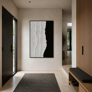 Black framed textured abstraction beside a dark entrance door and a slatted wooden bench.