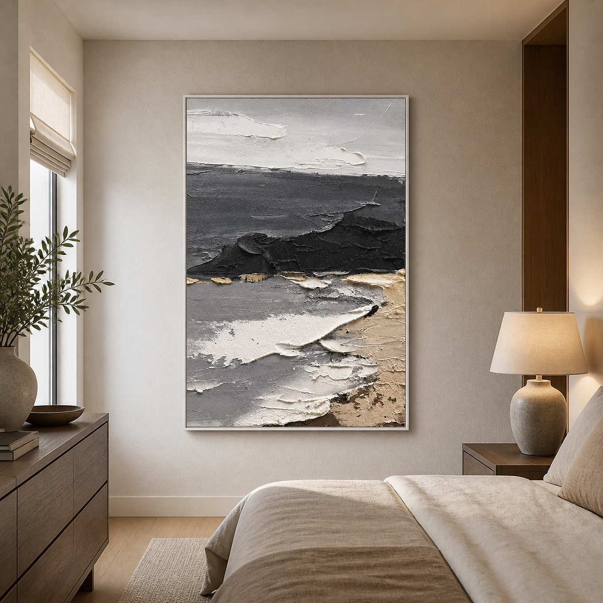 White framed layered coastal painting beside a beige bed in soft daylight.