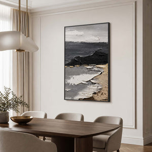 Black framed gray coastal artwork above a dark dining table with cream chairs.