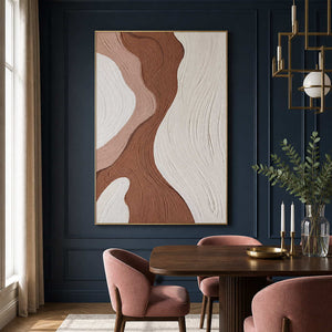 Gold framed abstract artwork beside a dark dining table and blush chairs.