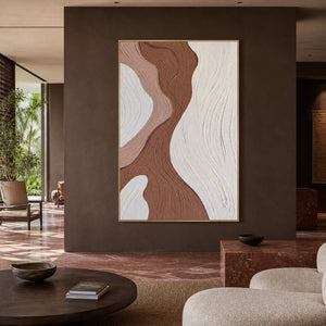 Gold framed brown and blush artwork above a hotel lobby seating area.