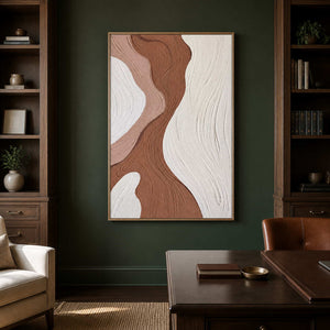 Wood framed abstract artwork between bookshelves beside a home office desk.