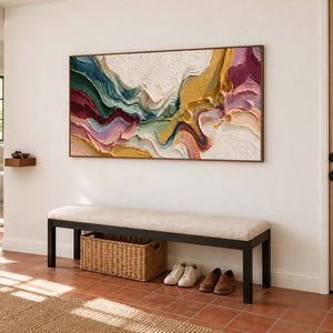 Multicolor abstract over a cream entryway bench with a woven basket beneath.