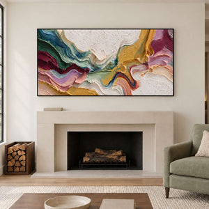 Wide textured color abstract above a pale fireplace beside a muted green armchair.