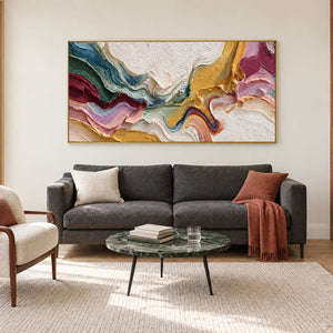 Multicolored folded abstract above a charcoal sofa with a rust cushion and throw.