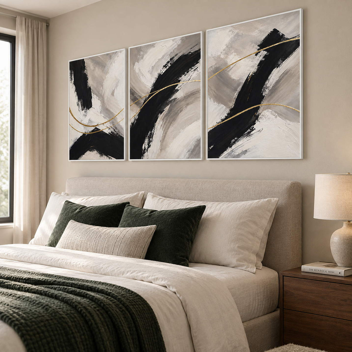 Three vertical abstract panels with black gestures, ivory fields, and gold lines, displayed in a bedroom with white frames.
