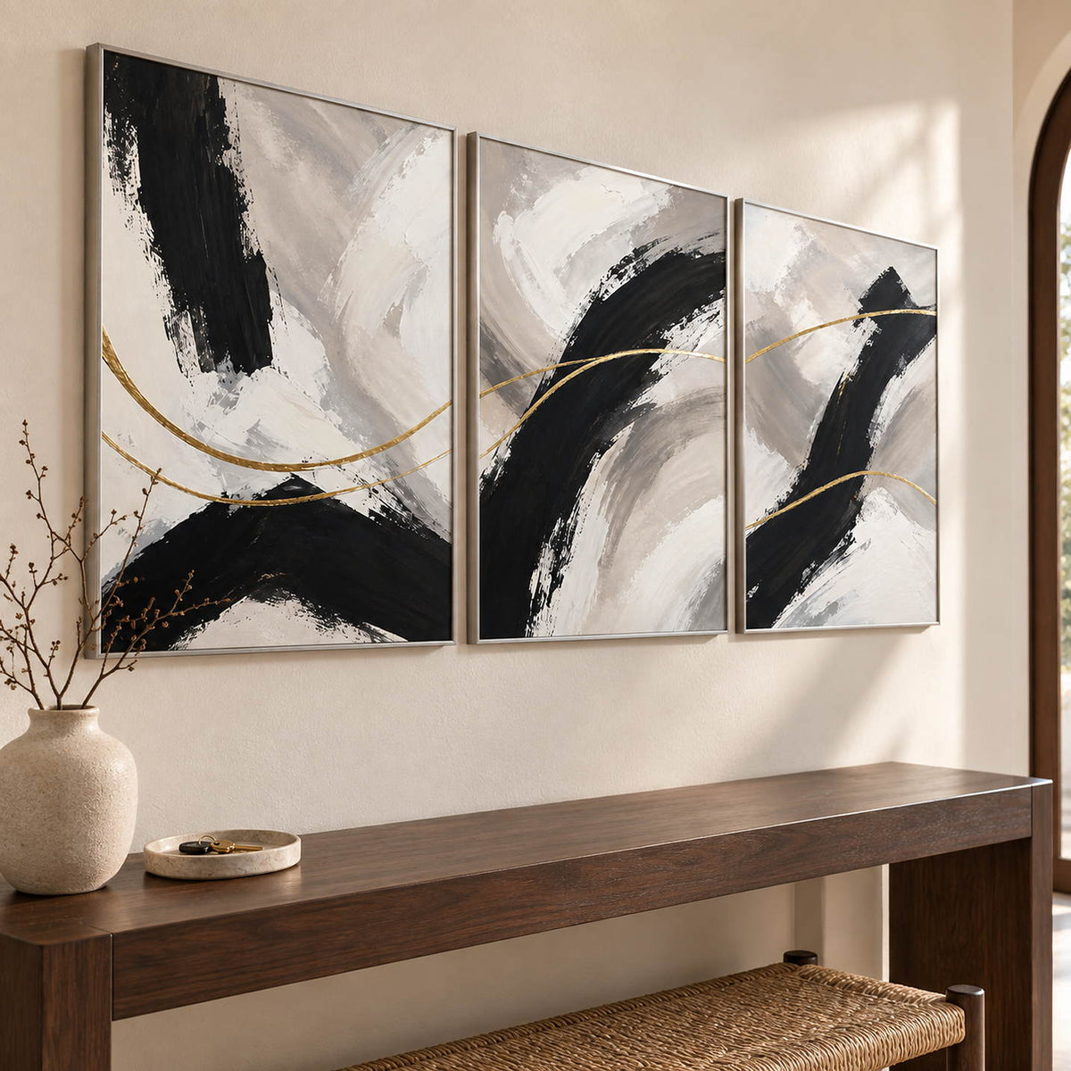 Three vertical abstract panels with black gestures, ivory fields, and gold lines, displayed in an entrance hall with silver frames.