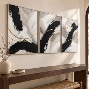 Three vertical abstract panels with black gestures, ivory fields, and gold lines, displayed in an entrance hall with silver frames.