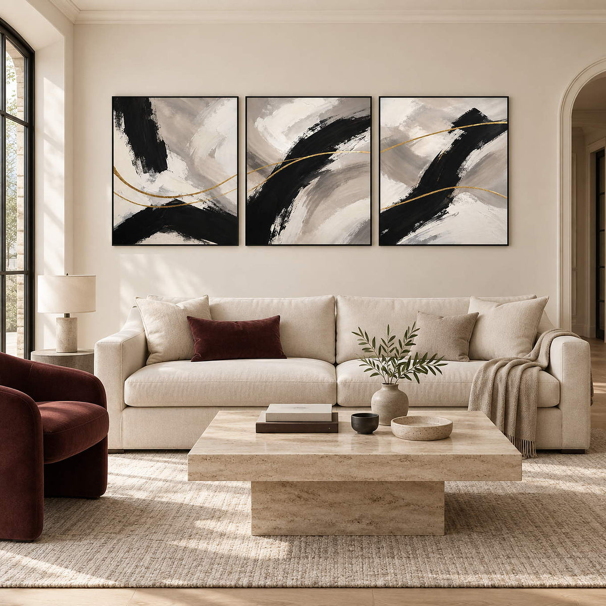 Three vertical abstract panels with black gestures, ivory fields, and gold lines, displayed in a living room with black frames.