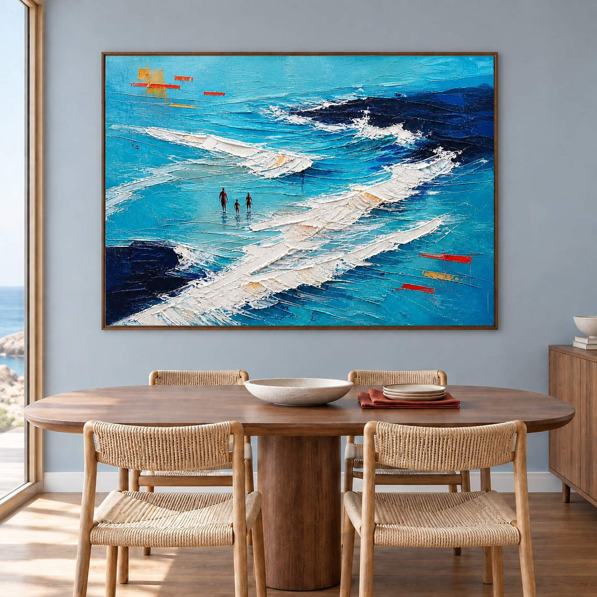 Turquoise coastal painting with three figures among white breaking waves in a brown wood frame in a dining room.