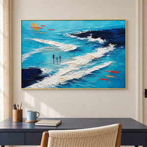 Turquoise coastal painting with three figures among white breaking waves in a gold frame in a home office.