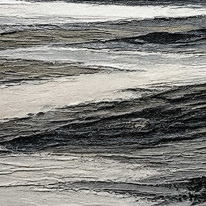 Close-up of layered black, ivory, and gray shoreline texture.