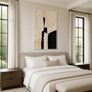 White framed monochrome abstract painting above a pale bed between tall windows and curtains.