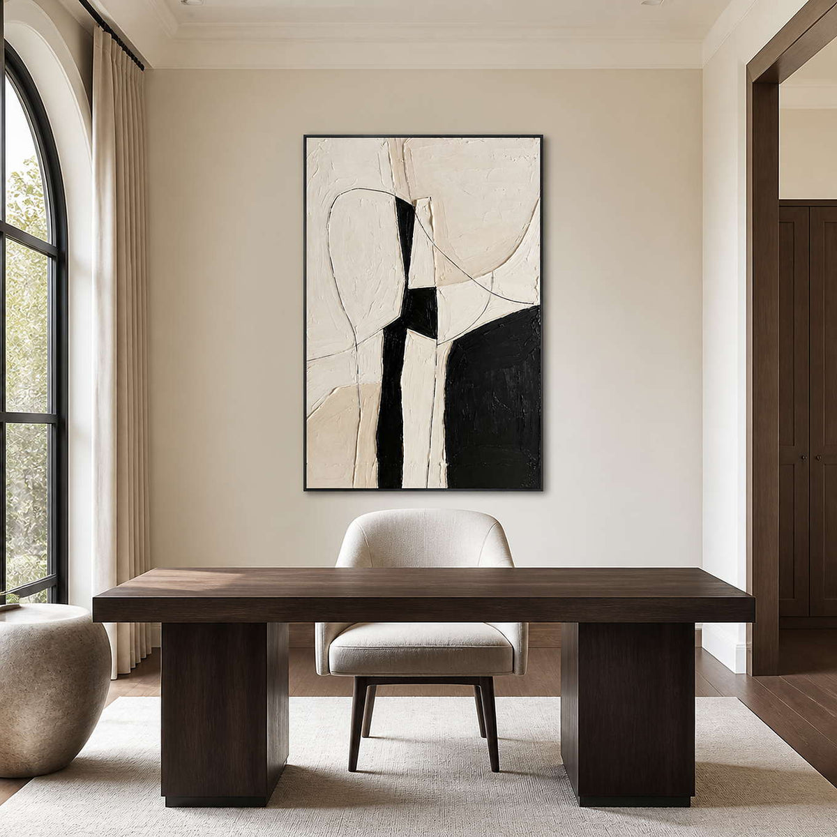 Black framed textured abstract painting above a dark wooden desk and upholstered study chair.