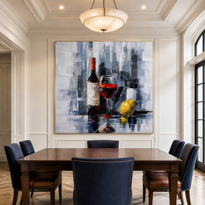 Gold framed wine and lemon painting above a banquet table with navy chairs.