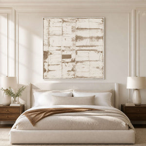 White-framed neutral abstract above an ivory bed with a brown throw and wooden nightstands.