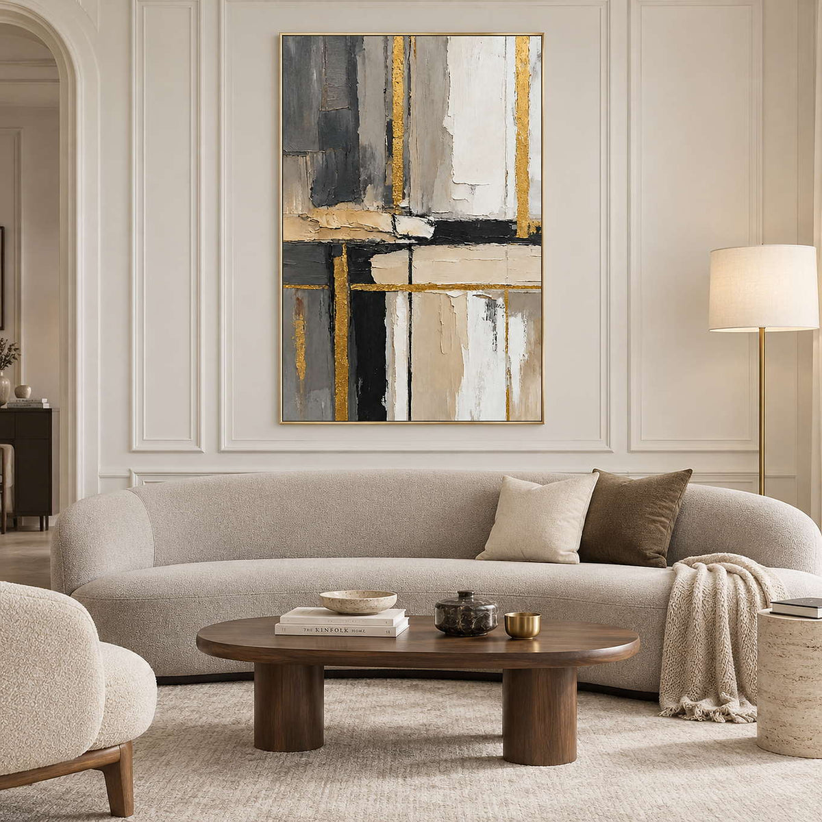 Neutral geometric painting above a curved cream sofa against a paneled wall.