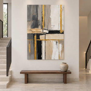 Gray, ivory, and black artwork above a wood bench beside a staircase.