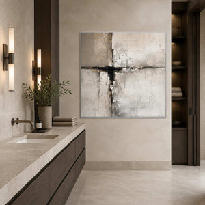 Silver framed pale abstract artwork beside a stone bathroom vanity and folded neutral towels.