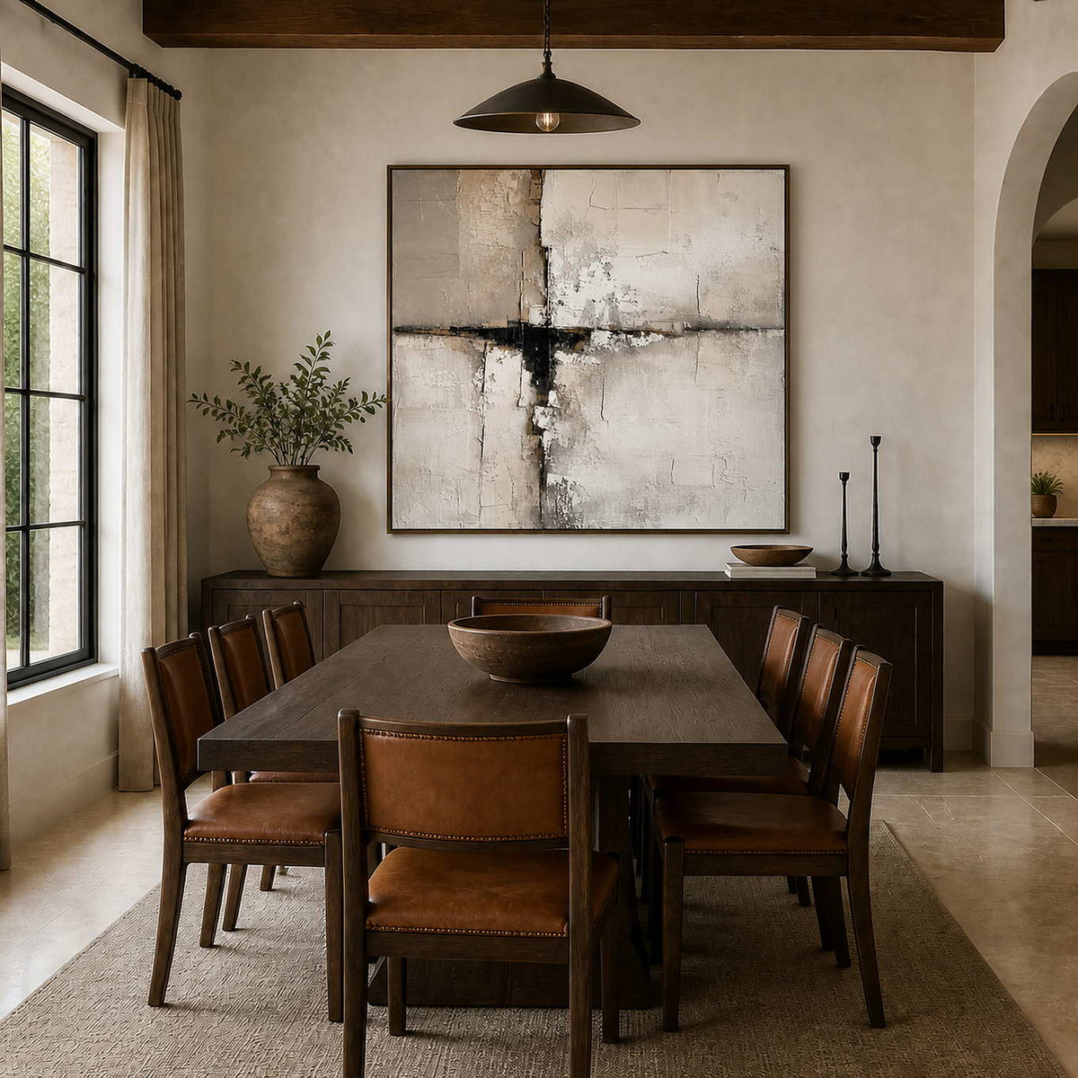 Wood framed abstract artwork above a sideboard behind a wooden dining table and leather chairs.