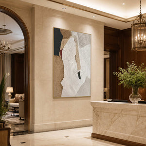 Gold framed earthy textured artwork beside a pale stone reception counter in a hotel lobby.