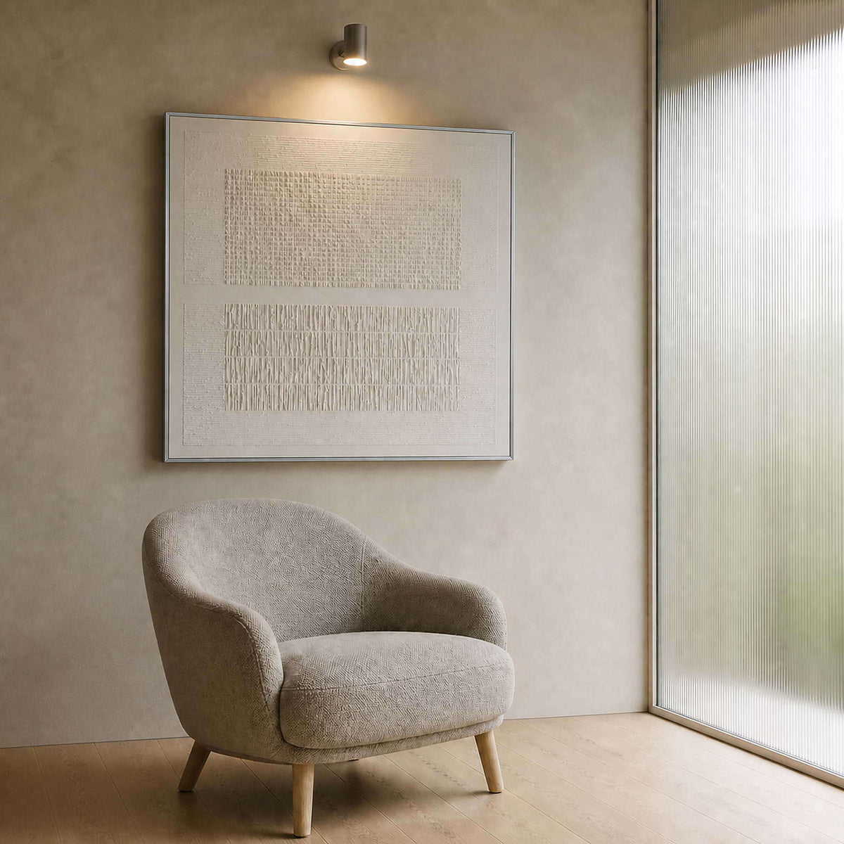 Ivory relief canvas beside a soft chair in a quiet sitting nook.