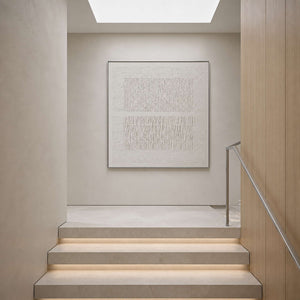 Minimalist white canvas displayed at a light-filled stair landing.