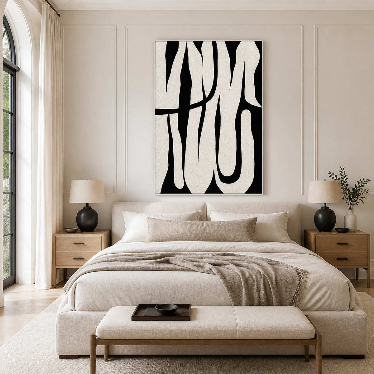 White framed black and white abstract artwork above a cream bed with wooden bedside tables.