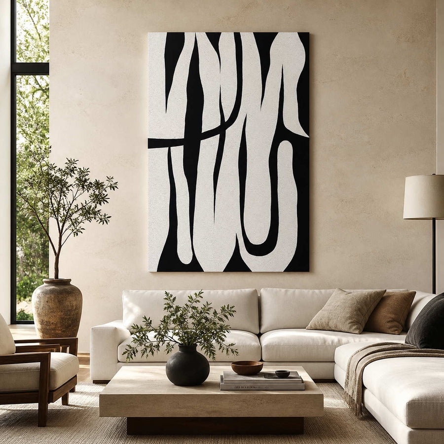 Frameless black and white curved abstract artwork above a cream sectional sofa near leafy plants.