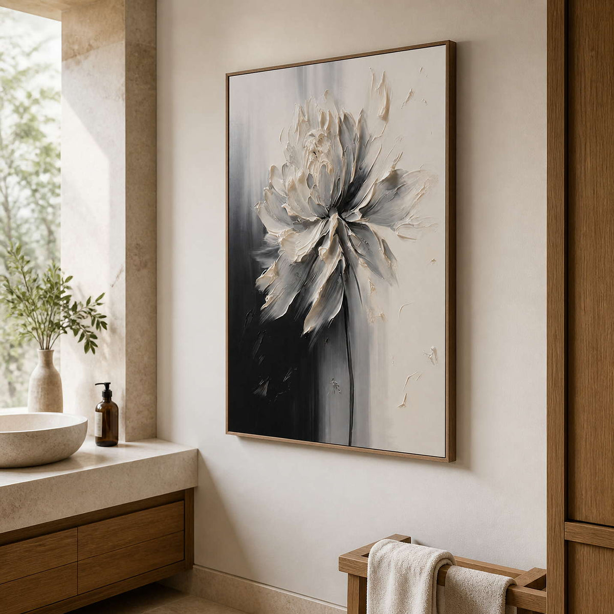 Wood framed monochrome floral artwork beside a stone bathroom basin and towels.