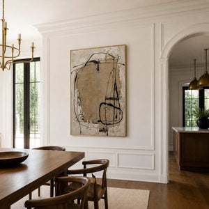 Gold-framed abstract wall art brings cream and sand tones to a dining room.