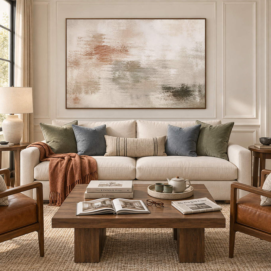 Neutral abstract painting with ivory, taupe, clay, and olive layered marks in a brown wood frame in a living room.