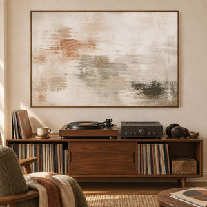 Neutral abstract painting with ivory, taupe, clay, and olive layered marks in a brown wood frame in a music listening room.
