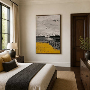 Wood framed yellow abstract artwork beside a bed with charcoal and mustard accent cushions.