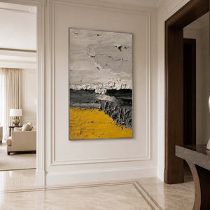 Silver framed yellow and charcoal abstract artwork on a paneled wall in an entryway.