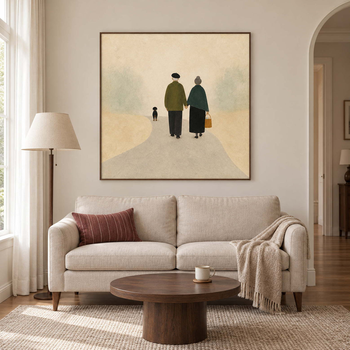 A couple walking away with a small dog on a pale path in a brown wood frame, displayed above a sofa in a living room.
