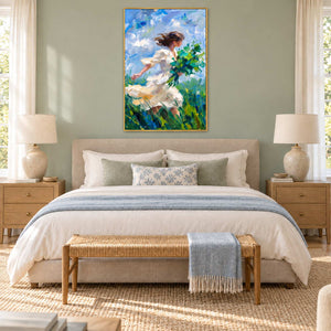 Walking into the Breeze in a gold frame above a cream bed with pale blue linen and a woven bench.