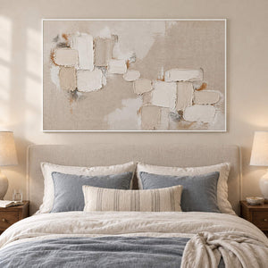 Textured abstract painting with raised ivory and taupe blocks in a white frame in a bedroom.